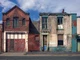 derelict houses and abandoned commercial property on a residential street with boarded up windows and decaying crumbling walls
